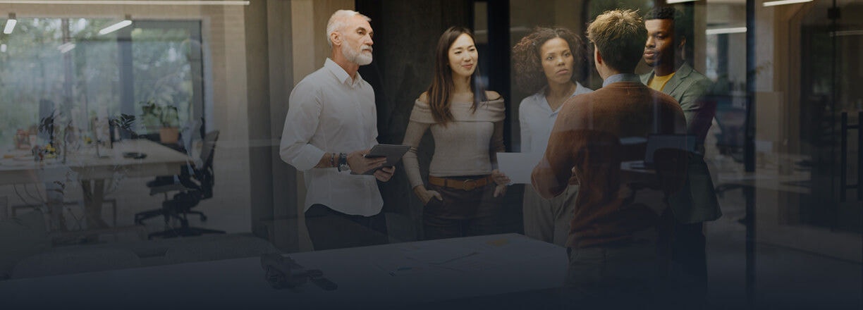 A group of colleagues discussing a project around a table in a modern office.